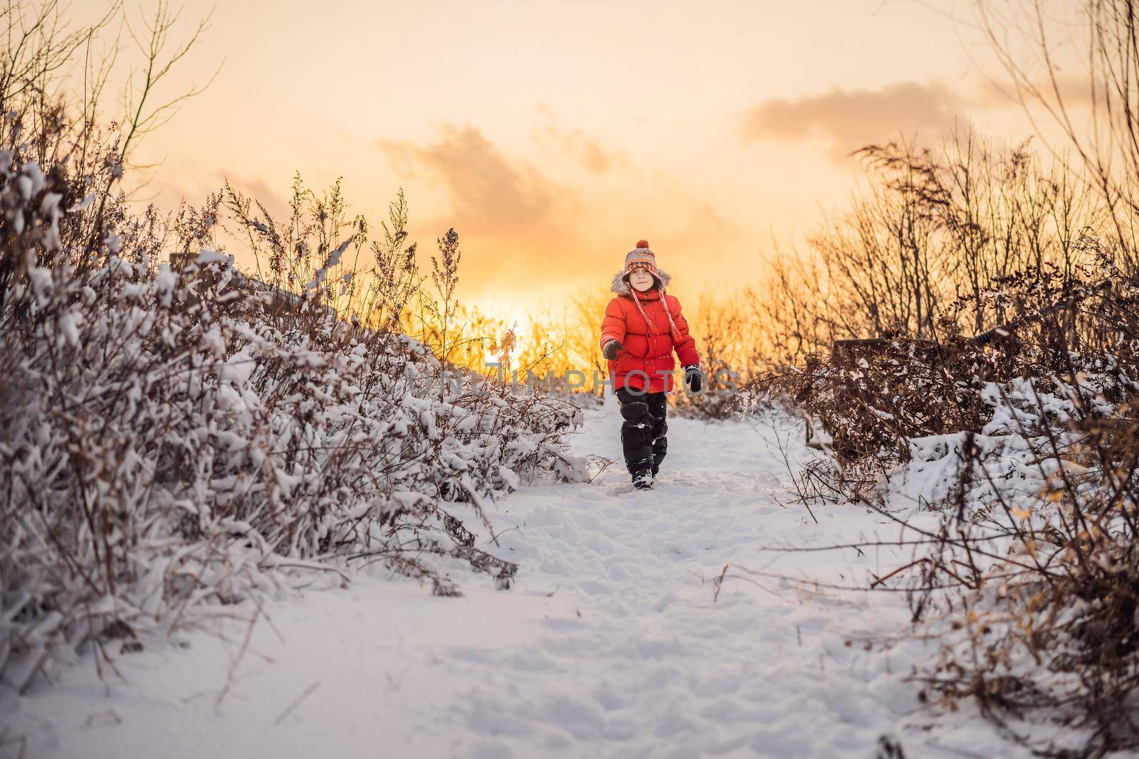 Cute boy in red winter clothes runs fun in the snow. Winter Fun Outdoor Concepts.