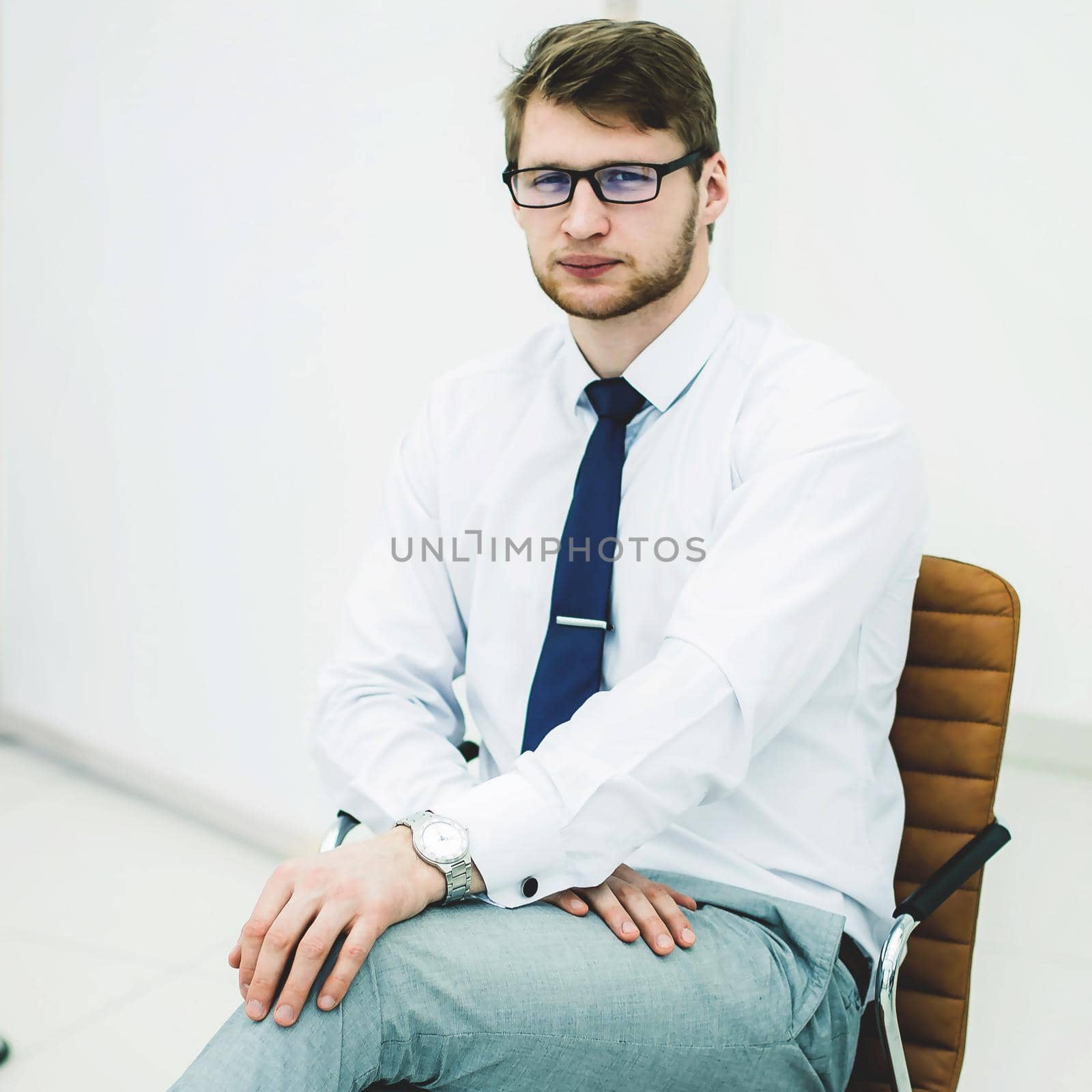 portrait of a businessman sitting on a chair in the spacious office.the photo has a empty space for your text