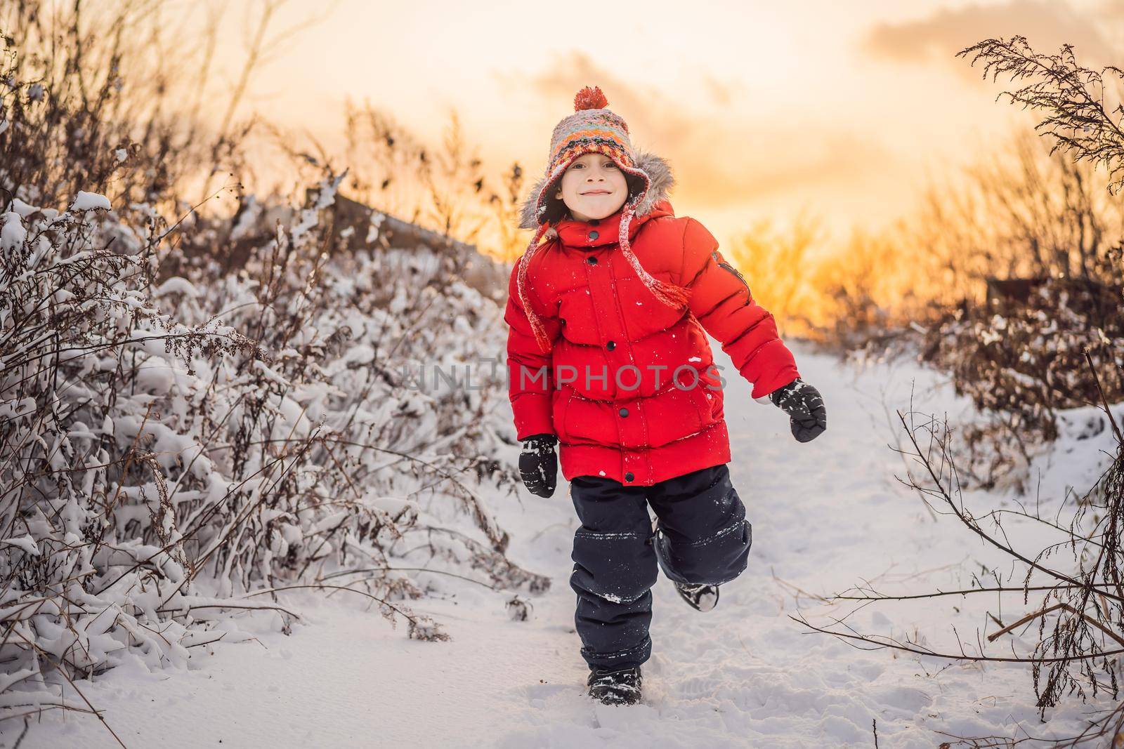 Cute boy in red winter clothes runs fun in the snow. Winter Fun Outdoor Concepts.