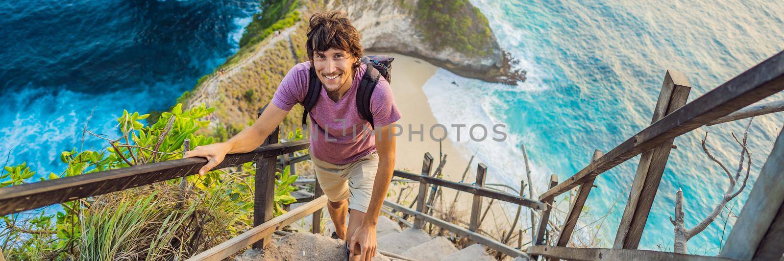 Family vacation lifestyle. Happy man stand at viewpoint. Look at beautiful beach under high cliff. Travel destination in Bali. Popular place to visit on Nusa Penida island. BANNER, LONG FORMAT