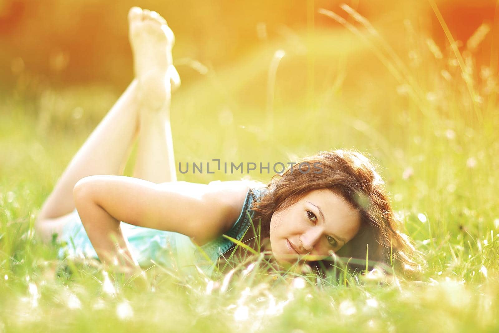 Beautiful young woman lying on summer field