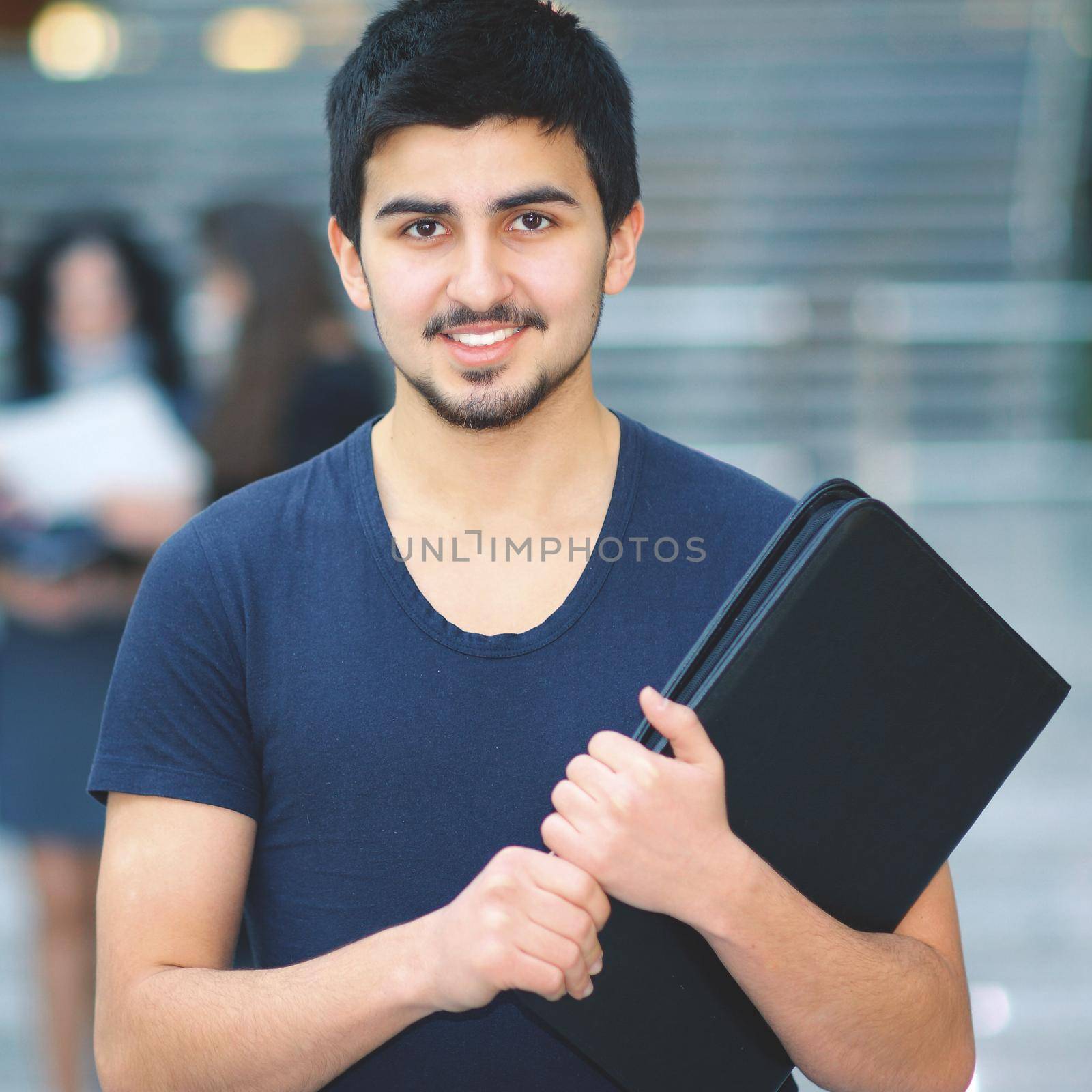 Young successful business with a folder smiling and looking at the picture by SmartPhotoLab