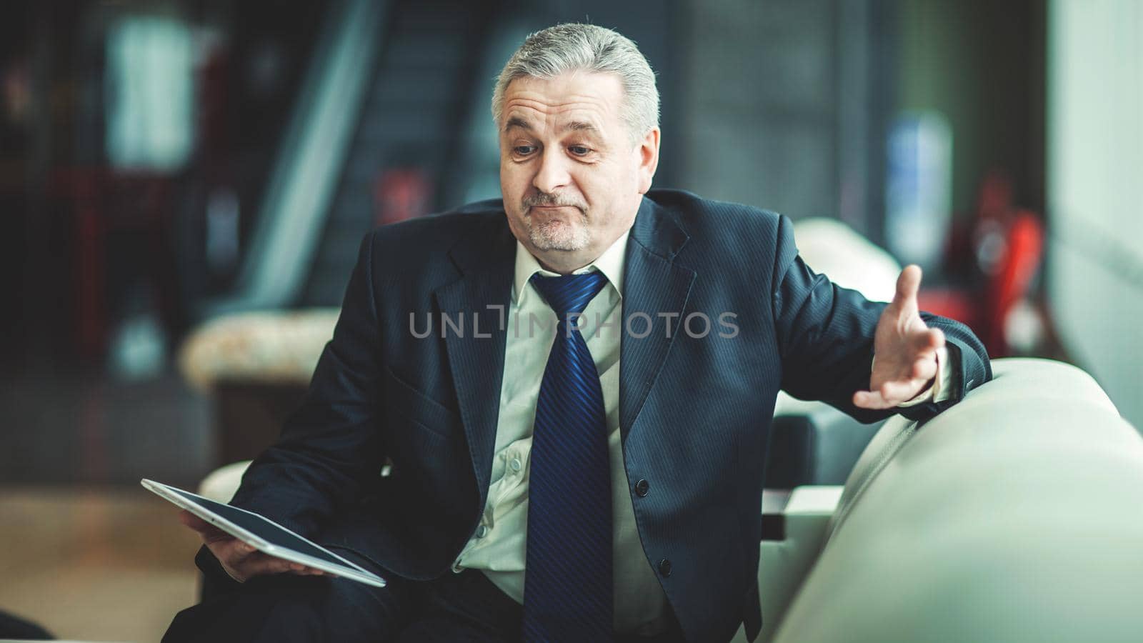smiling businessman with digital tablet sitting on sofa in the office