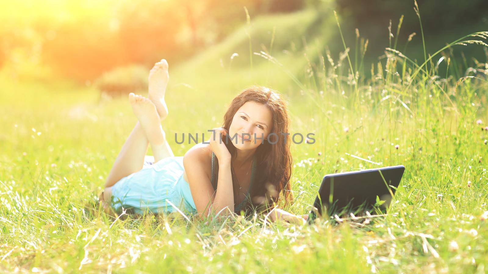 Beauty girl with laptop outdoors in a park on a sunny day