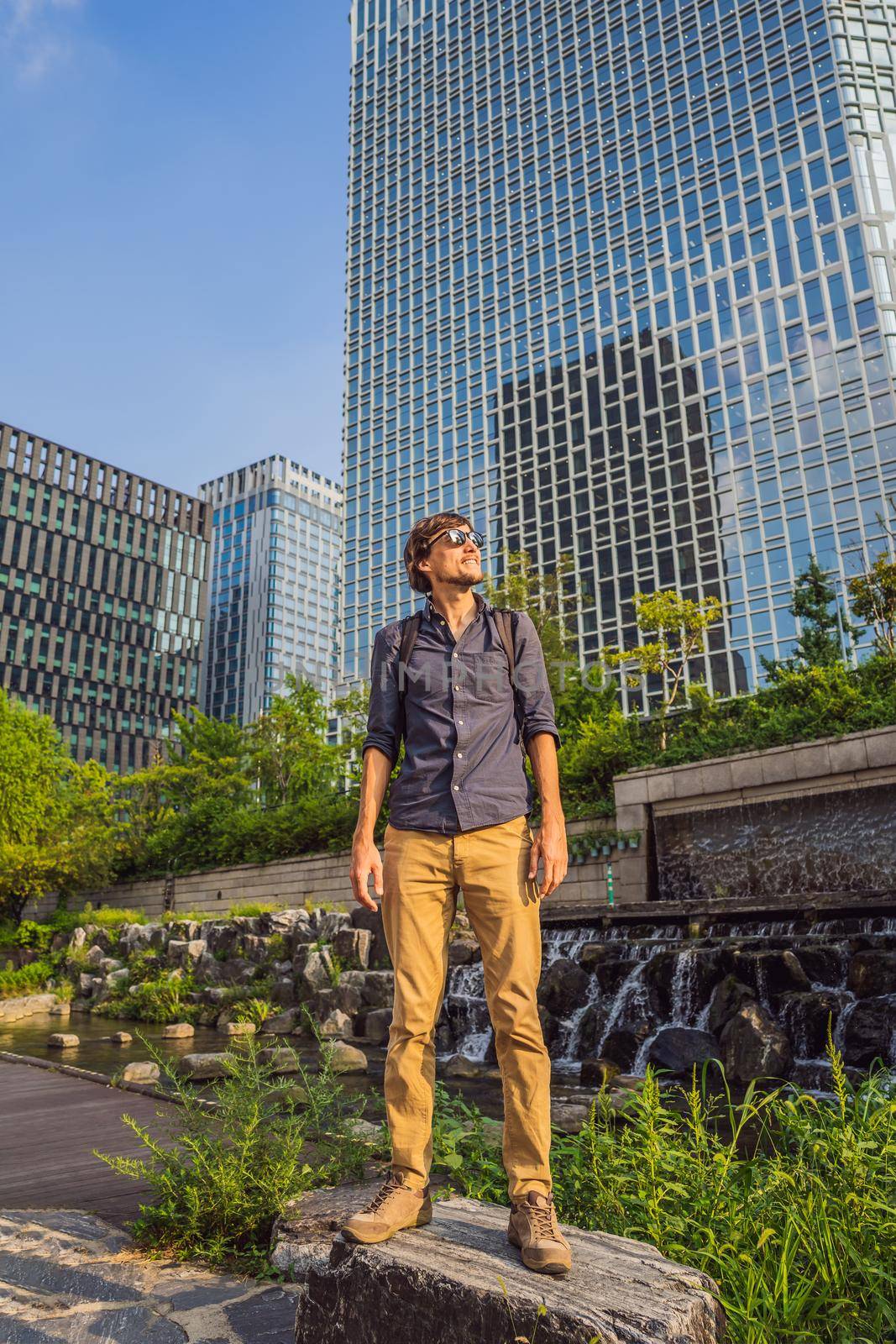 Young man tourist in Cheonggyecheon stream in Seoul, Korea. Cheonggyecheon stream is the result of a massive urban renewal project. Travel to Korea Concept by galitskaya