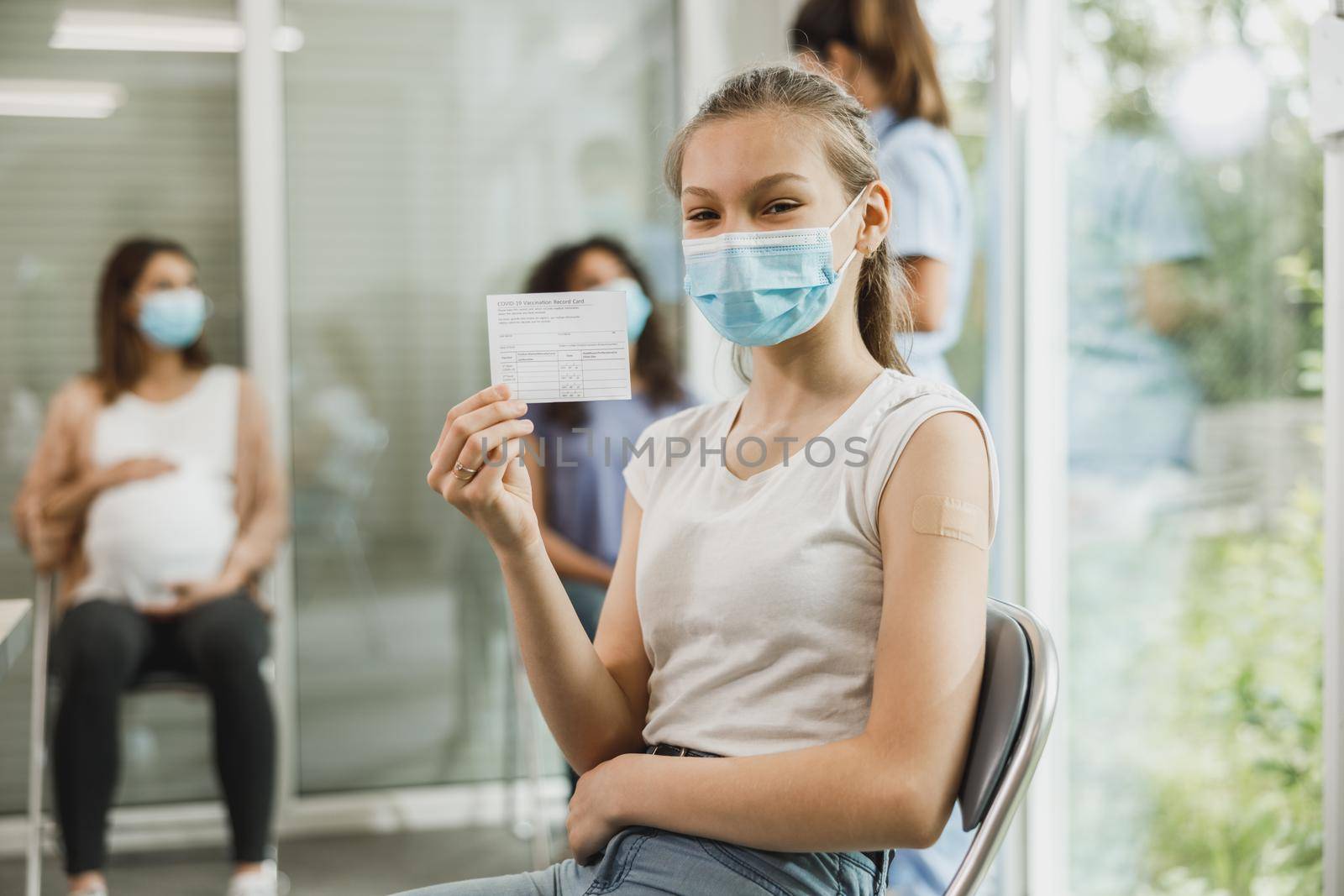 A smiling teenager girl with a smile showing vaccination certificate after receiving the Covid-19 vaccine.