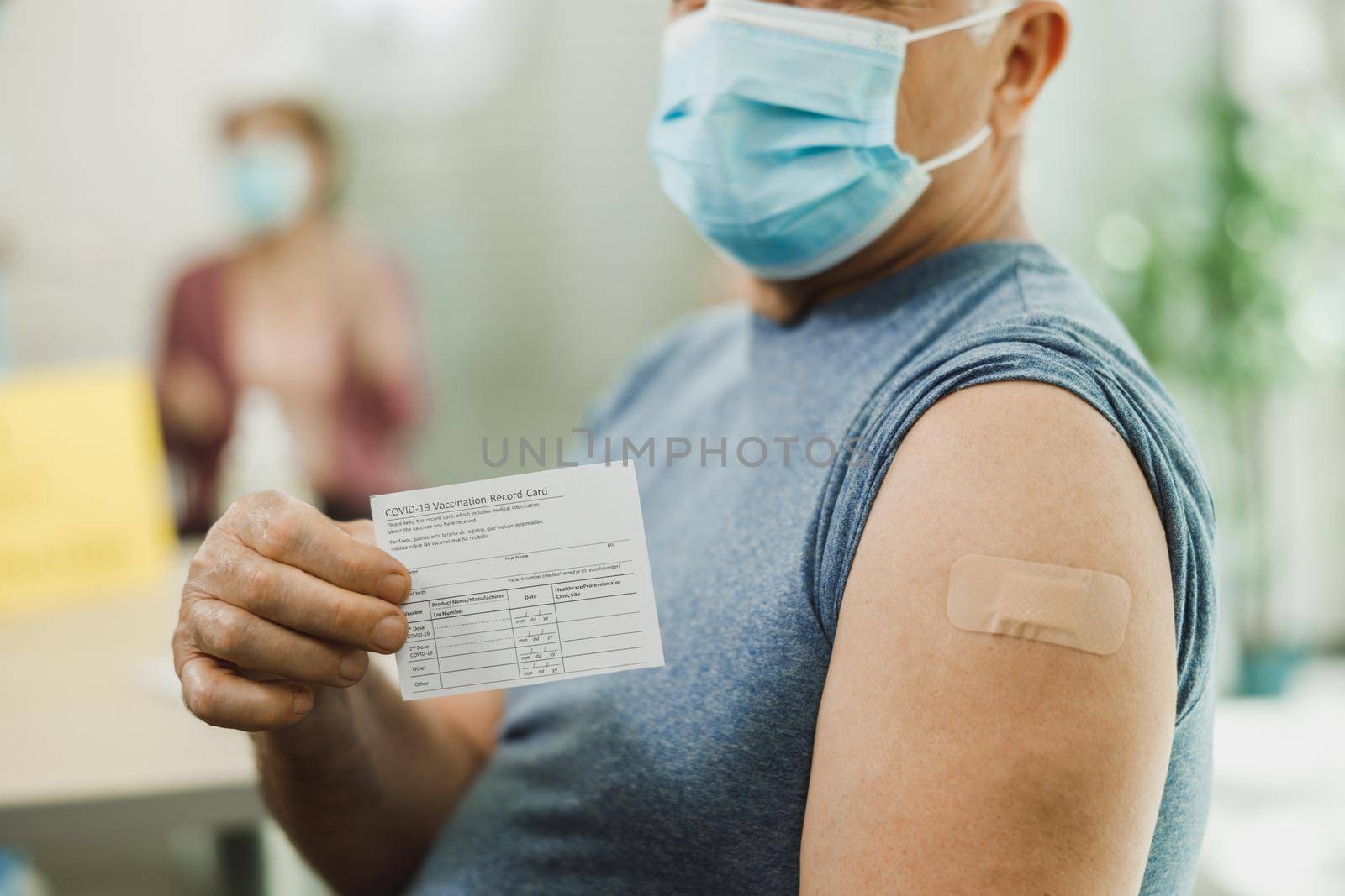 Senior Man Holding Covid-19 Vaccination Record Card by MilanMarkovic78