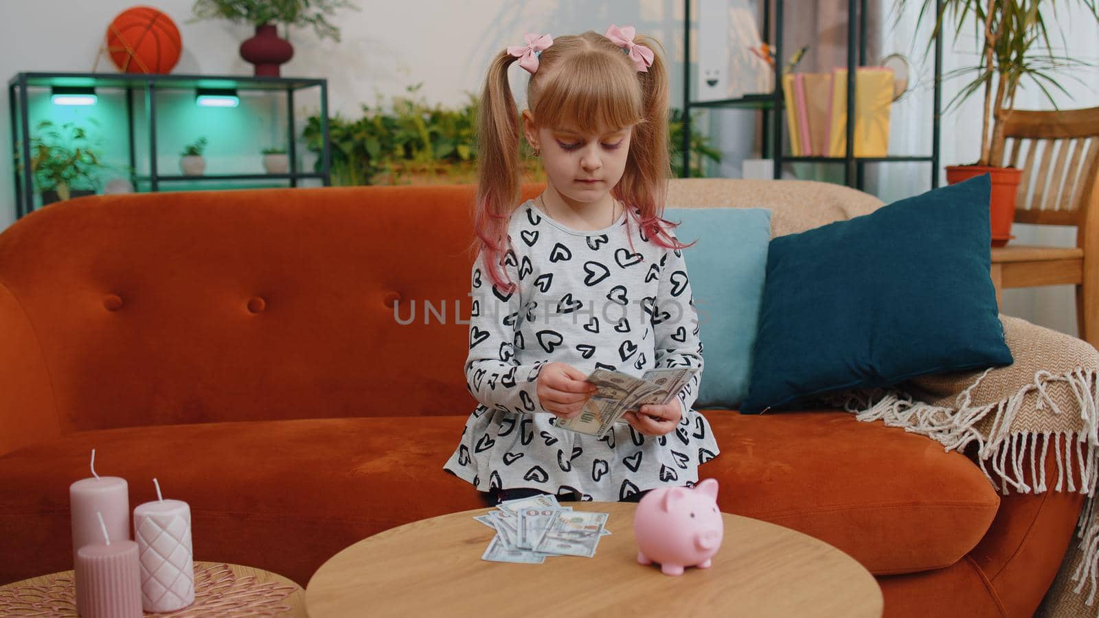 Little toddler kid girl counting money dollar banknotes at home desk with piggybank. School teen children save money, pocket cash for future needs, education, purchases, learn, economy from childhood