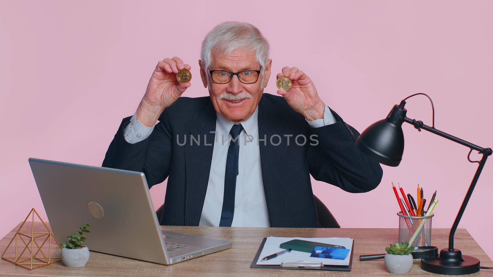 Elderly businessman showing golden bitcoins. Achievement career wealth, cryptocurrency investment mining money income future technology. Senior man freelancer fooling, making faces at office