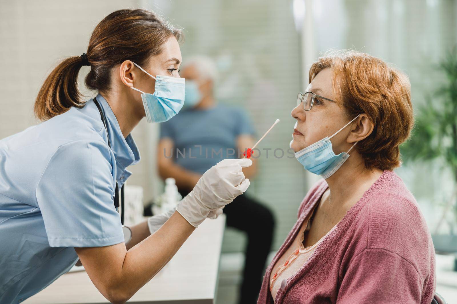 A nurse takes sample from nose of a senior woman to antigen test for coronavirus.