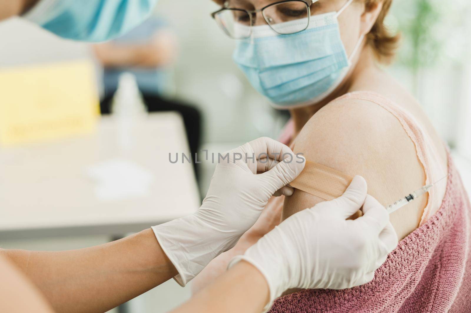 Close-up of a nurse applying a band aid to a senior woman after receiving a vaccine due to coronavirus epidemic.