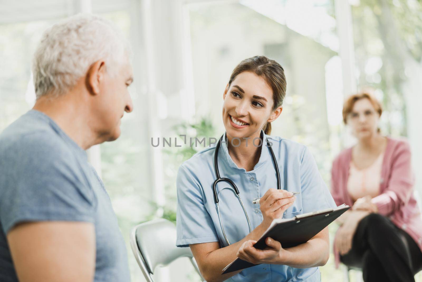 Nurse talking and doing an emotional support to a senior patient at hospital waiting room.