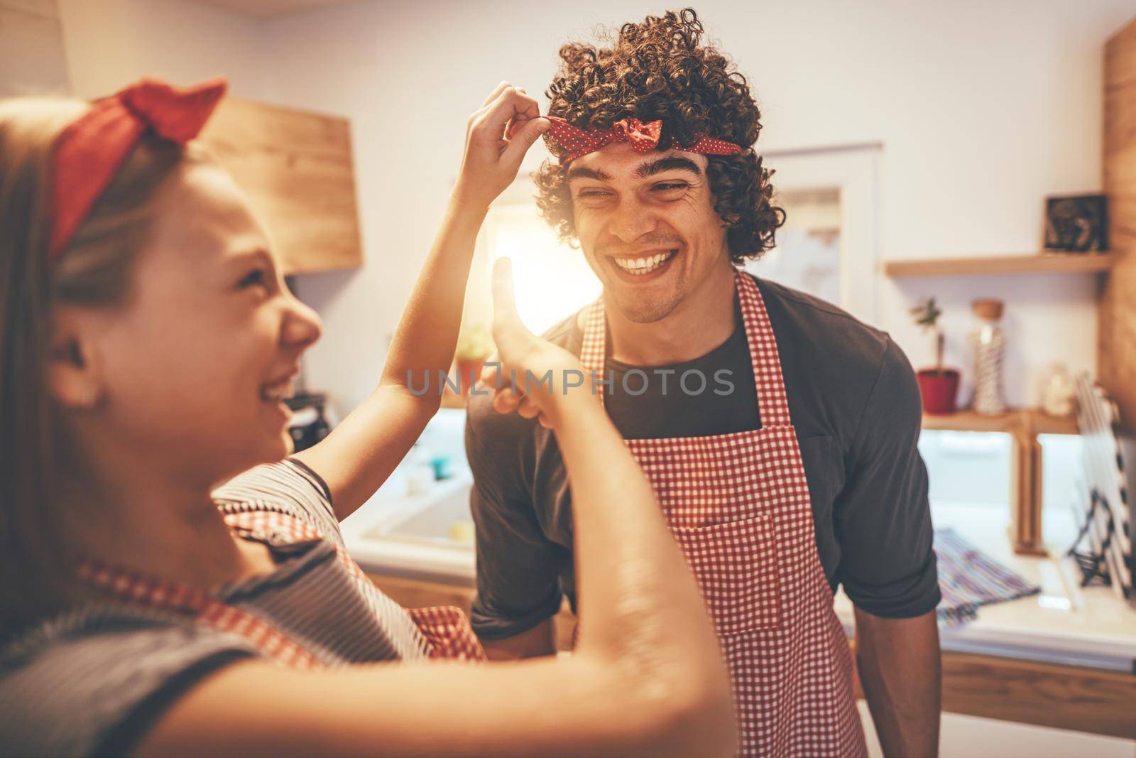 Happy father and his daughter enjoy and having fun in making and having healthy meal together at their home kitchen. The girl binds the ribbon around her father's head