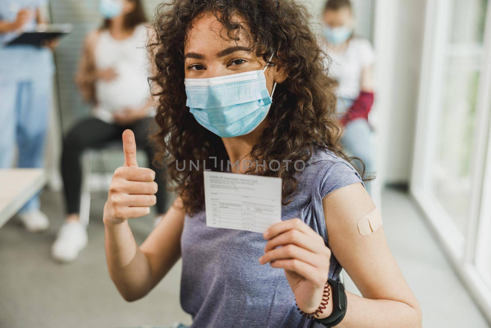 An African American teenager girl with a smile showing thumb up after receiving the Covid-19 vaccine.