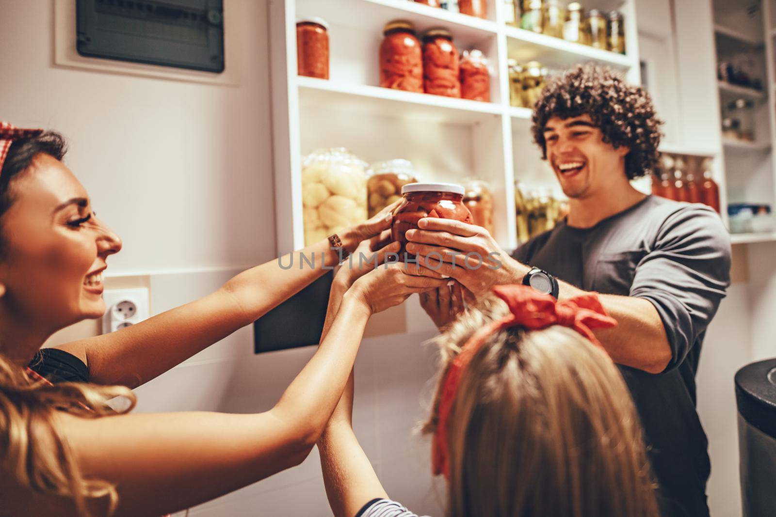 A happy family takes jars with pickled vegetables from the pantry shelf.