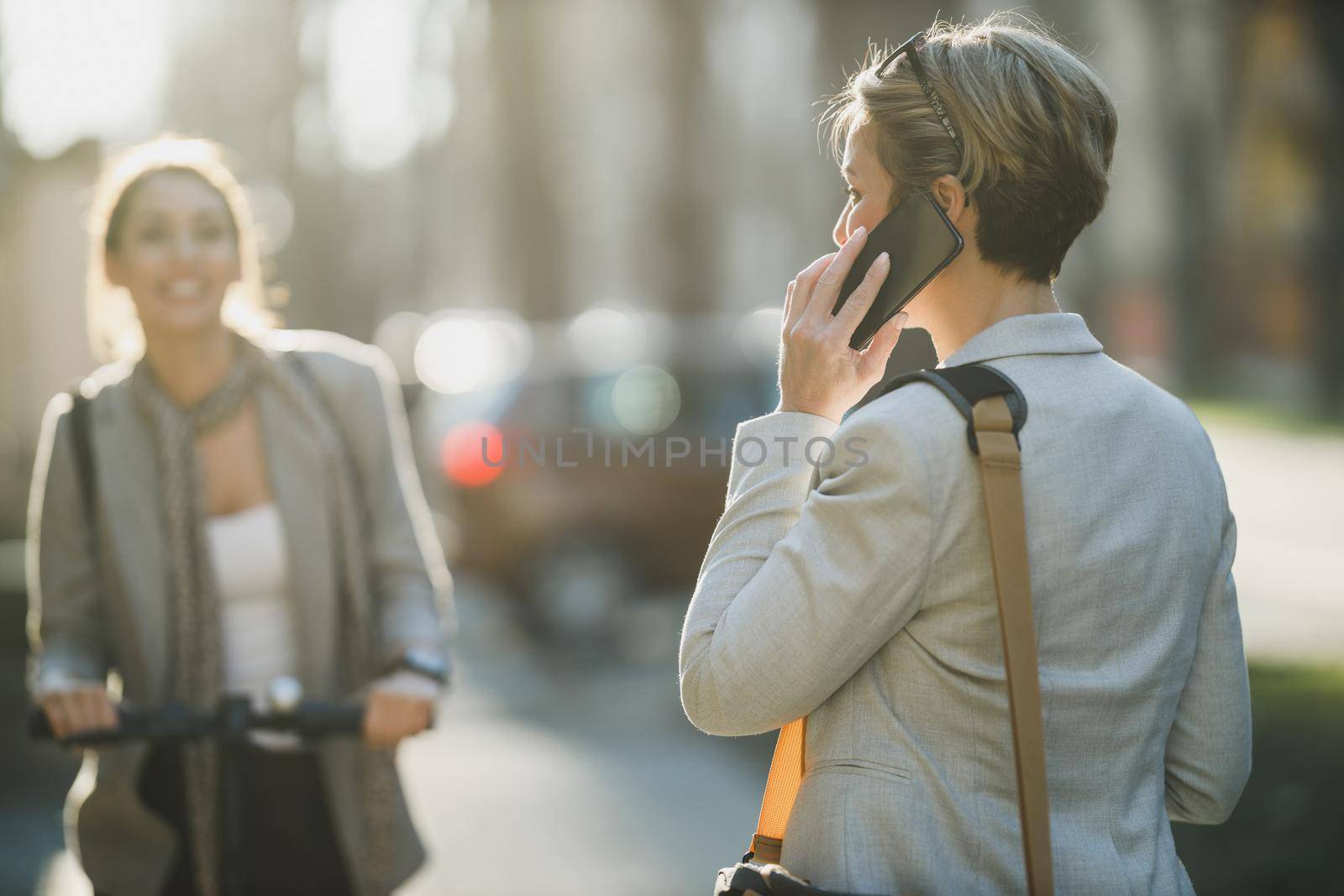 Rear view of a mature business woman using a smartphone while going to work.
