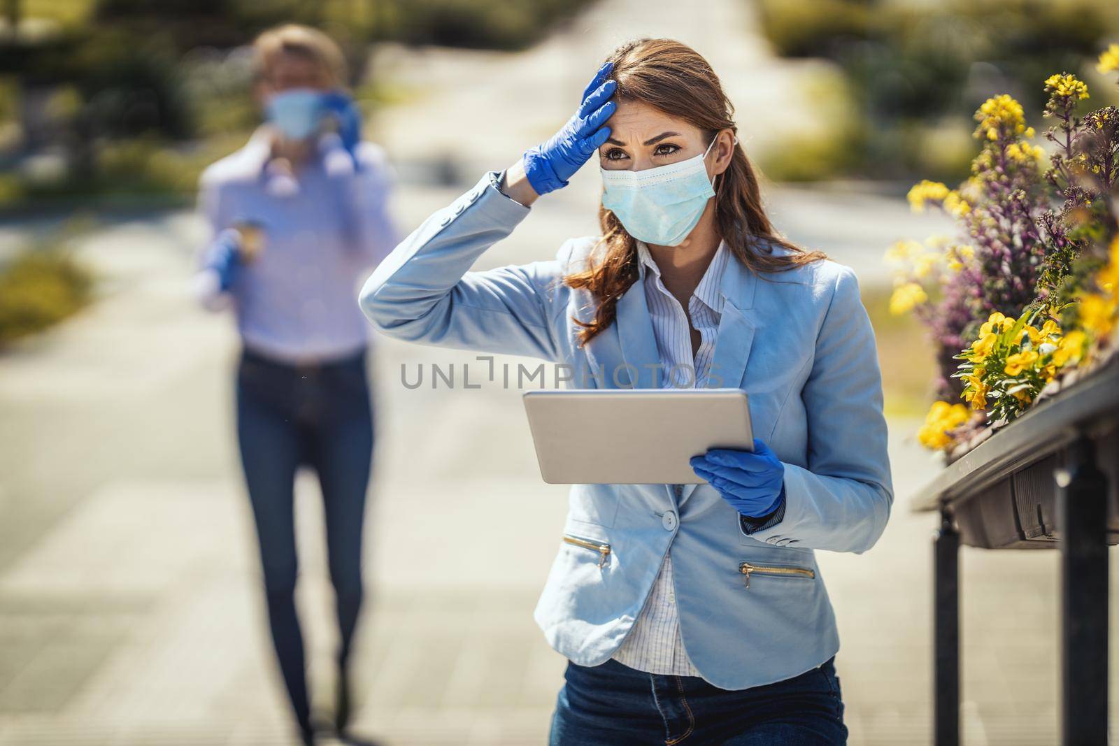 Young business woman with protective mask on her face is looking something on her digital tablet during covid 19 pandemic.