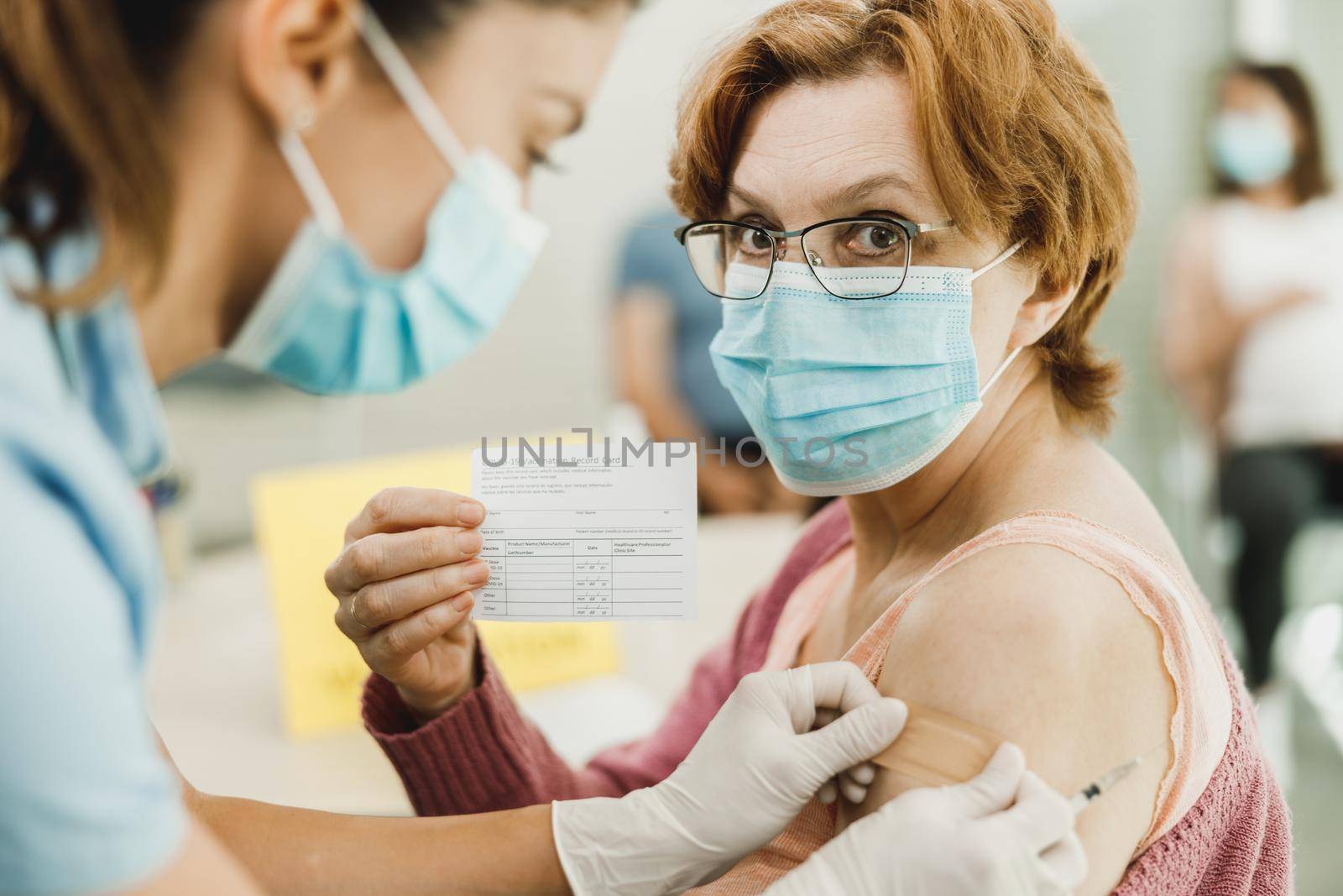 A nurse applying a band aid to a senior woman after receiving a vaccine due to coronavirus epidemic.