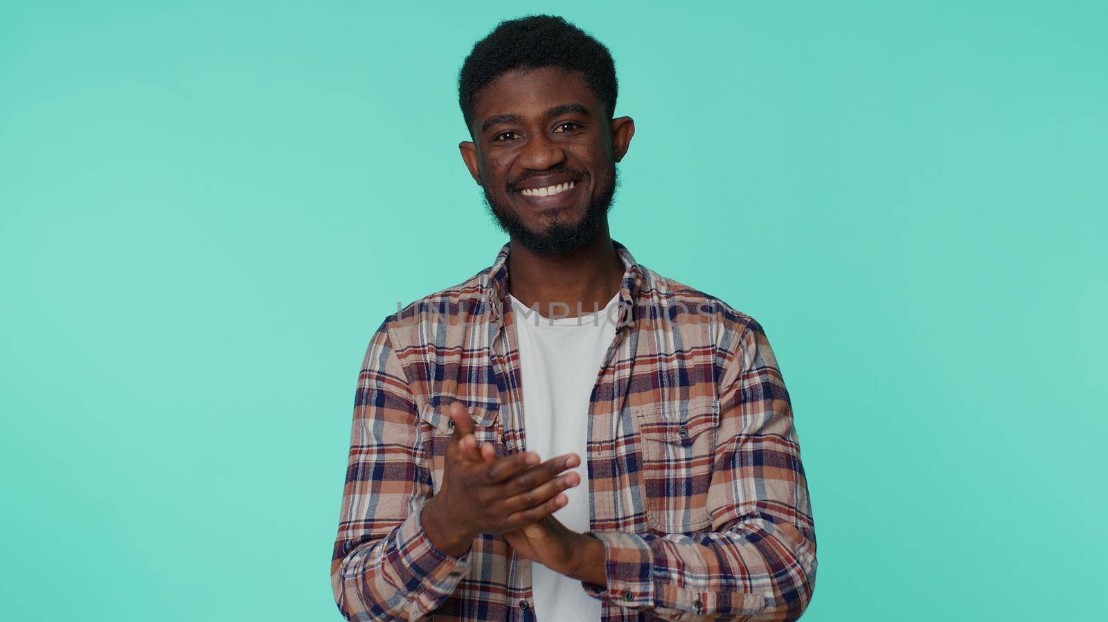 Great job, nice. Cheerful positive african american man in shirt showing thumbs up and nodding in approval, successful good work. Young one guy on blue studio background. People sincere emotions