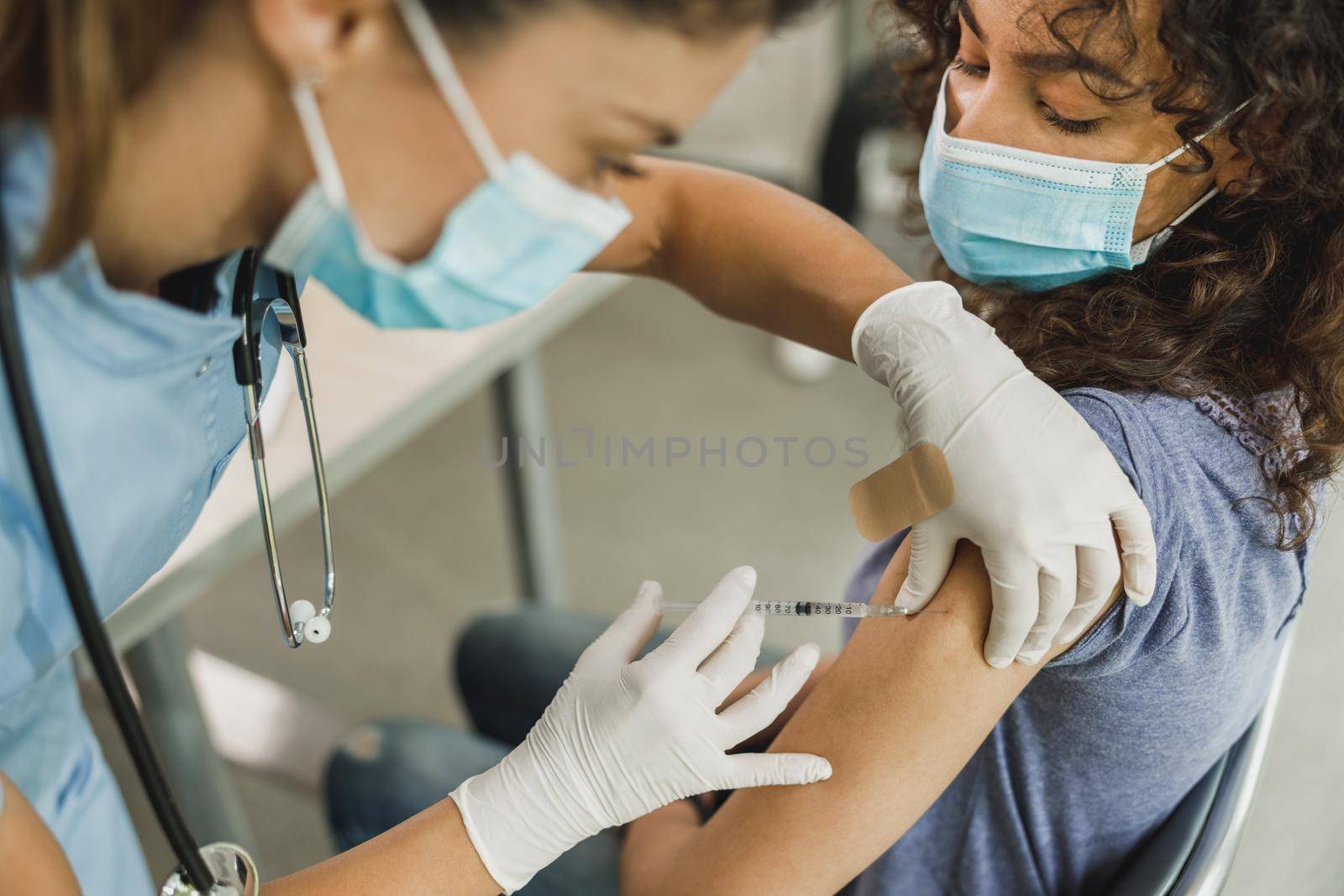 Close-up of a nurse giving a vaccine to African American teenager girl due to coronavirus pandemic.