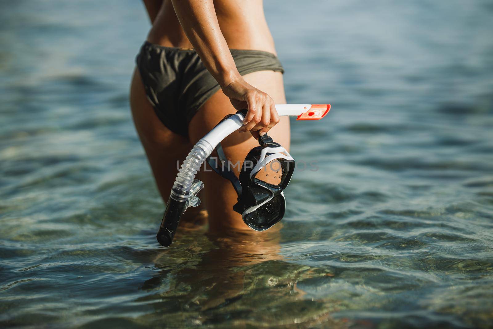Close-up of an attractive woman with her scuba mask and snorkel walking through the sea after snorkeling.
