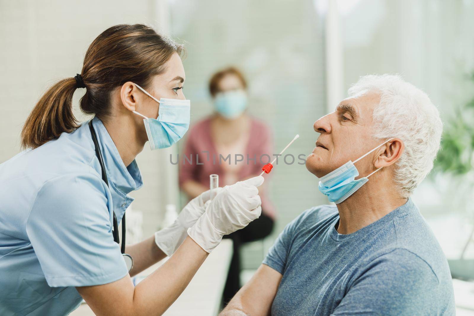 A nurse takes sample from nose of a senior man to antigen test for coronavirus.