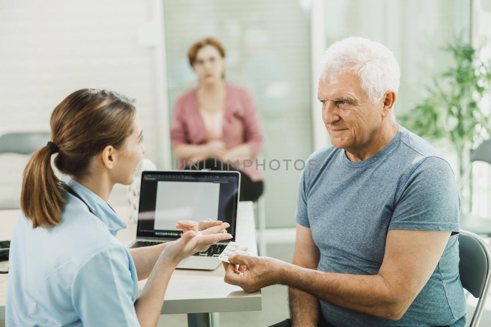 Caring Nurse Talking To Senior Man At Hospital Waiting Room by MilanMarkovic78