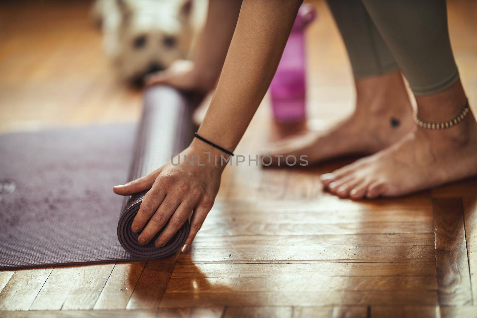 Close up of a womans hands is rolling up exercise mat and preparing to doing yoga. 