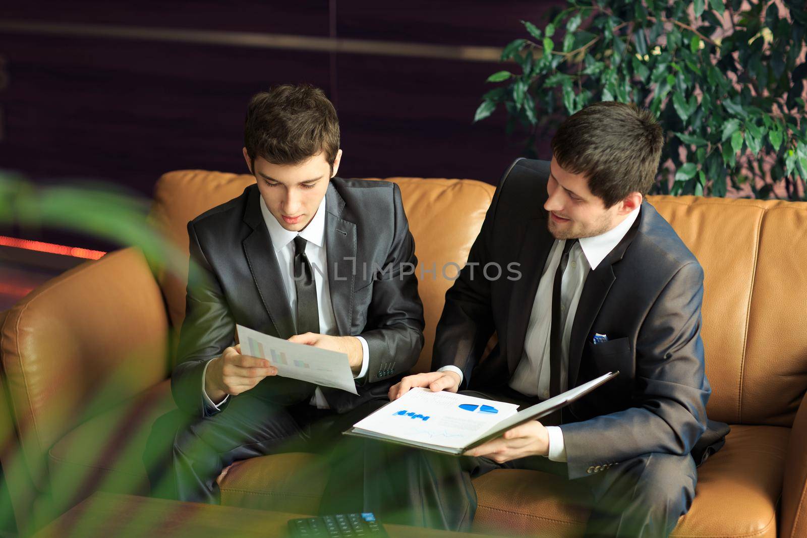 Image of two young businessmen discussing project at meeting by SmartPhotoLab