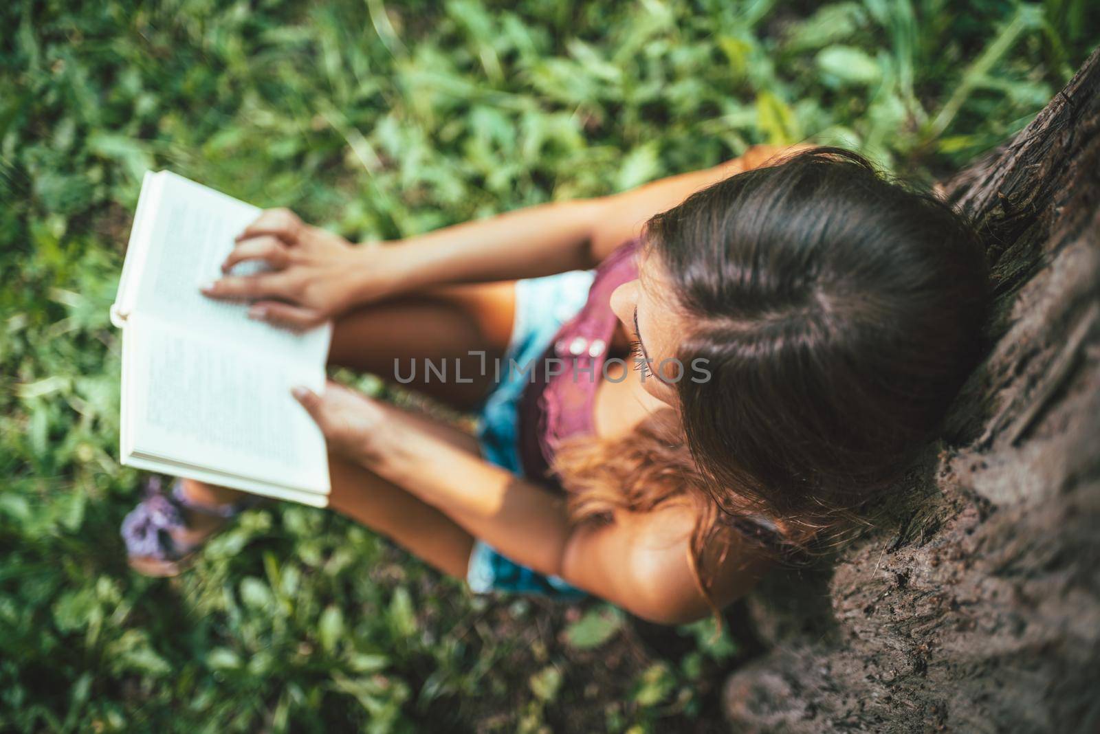 Top view of attractive young woman is enjoying her time outside reading book in park.