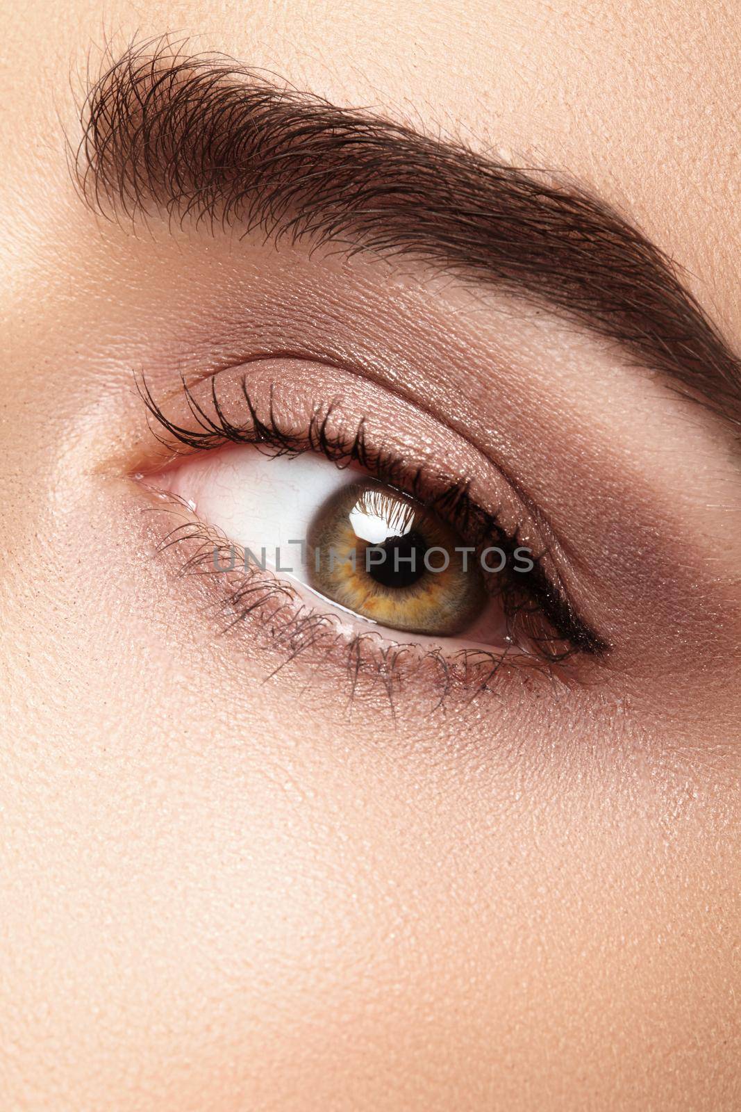 Beautiful macro of female eye with classic clean makeup. Perfect shape eyebrows, beige eyeshadows. Cosmetics and make-up. Care about eyes