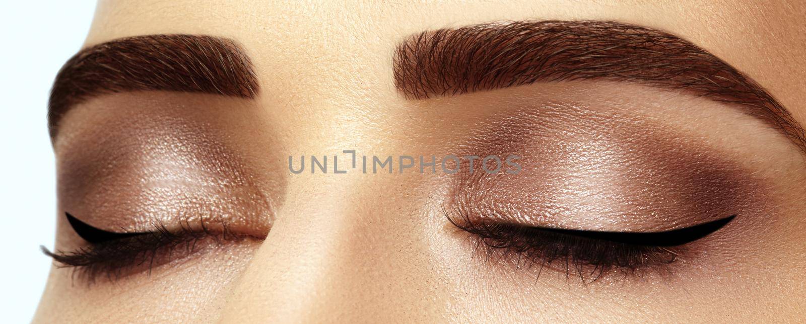Perfect shape of eyebrows, brown eyeshadows and long eyelashes. Closeup macro shot of fashion smoky eyes visage by MarinaFrost