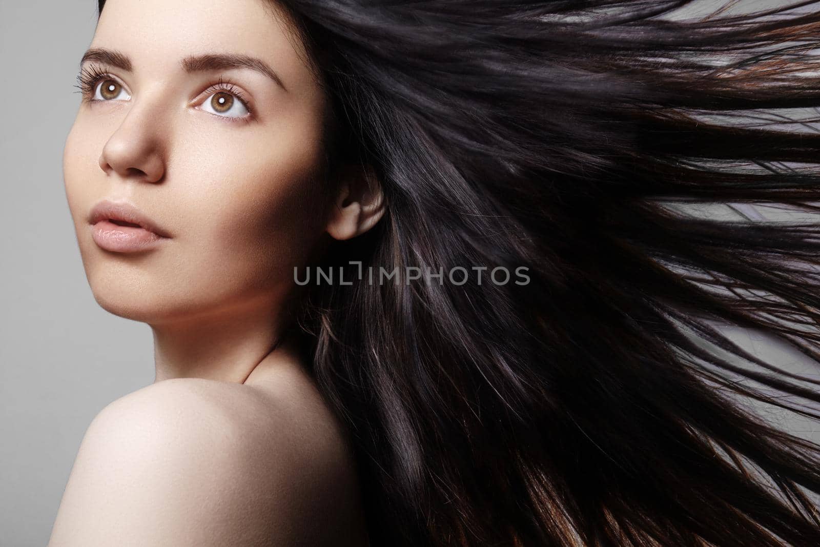 Beautiful young woman model with flying brown color hair. Beauty portrait with clean skin, glow glamour fashion makeup. Make up, curly hairstyle. Haircare, make-up. Horizontal beauty portrait