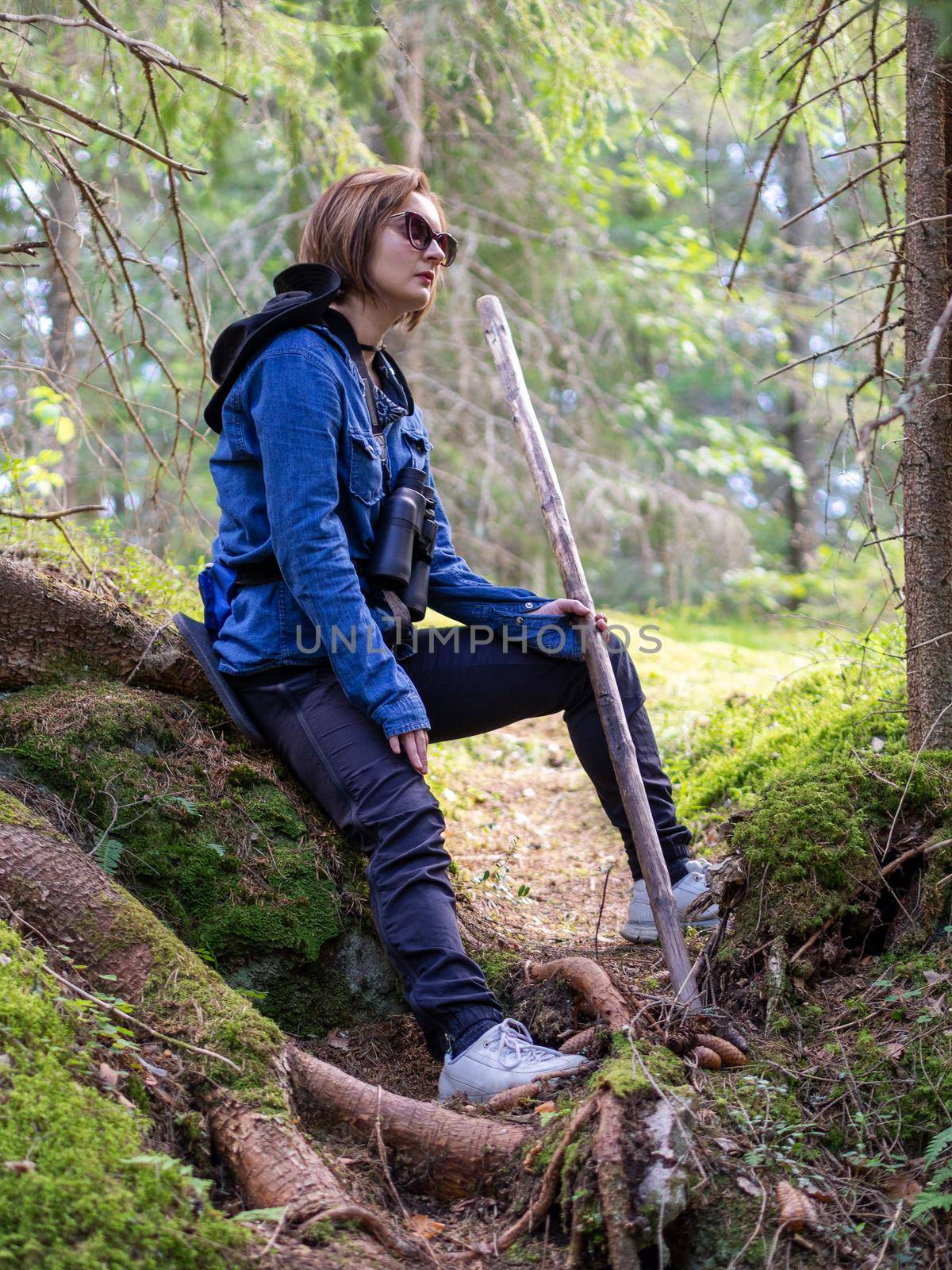 Hiking. Woman hiker in forest taking a rest sitting down. Beautiful young Caucasian model. Photo
