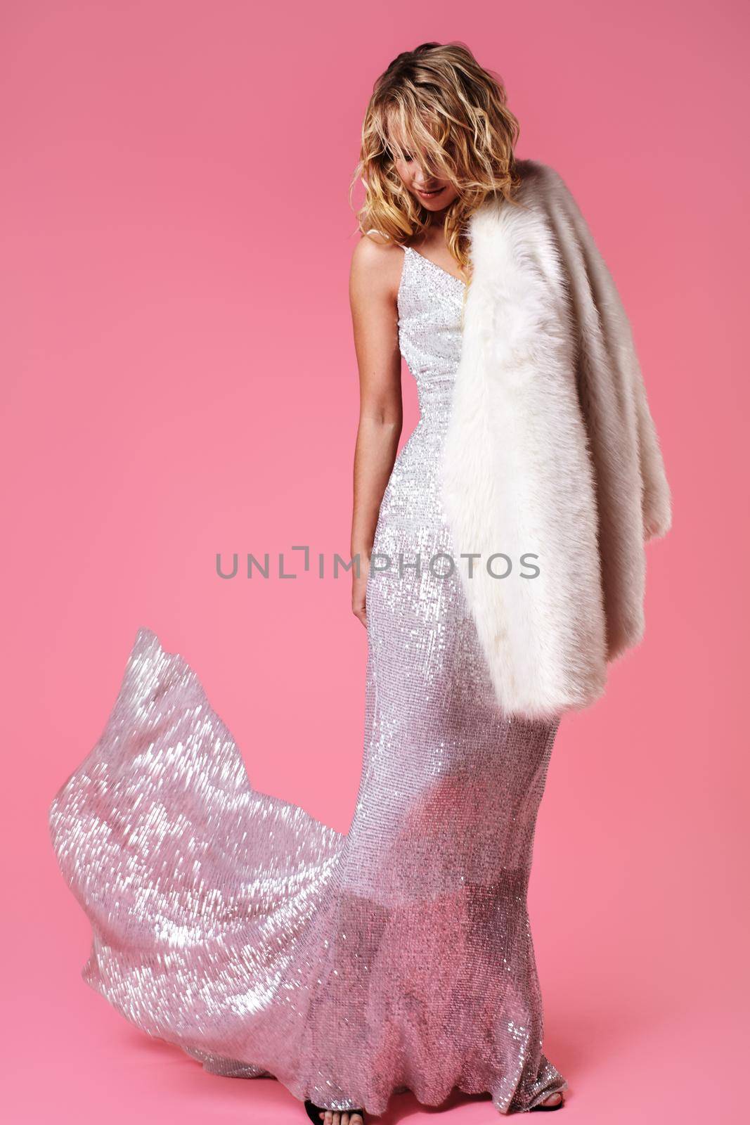 Young Lady in Fashion Dress and Fur Coat. Sexy Woman Posing on Pink Background in Luxury Fashionable Clothes and Shoes. Glamour Style