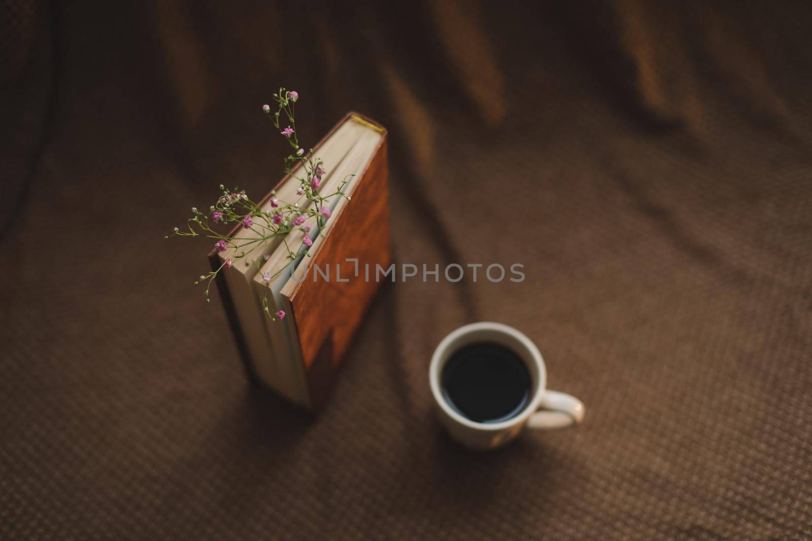 A book with flowers and cup of coffee on dark background top view.