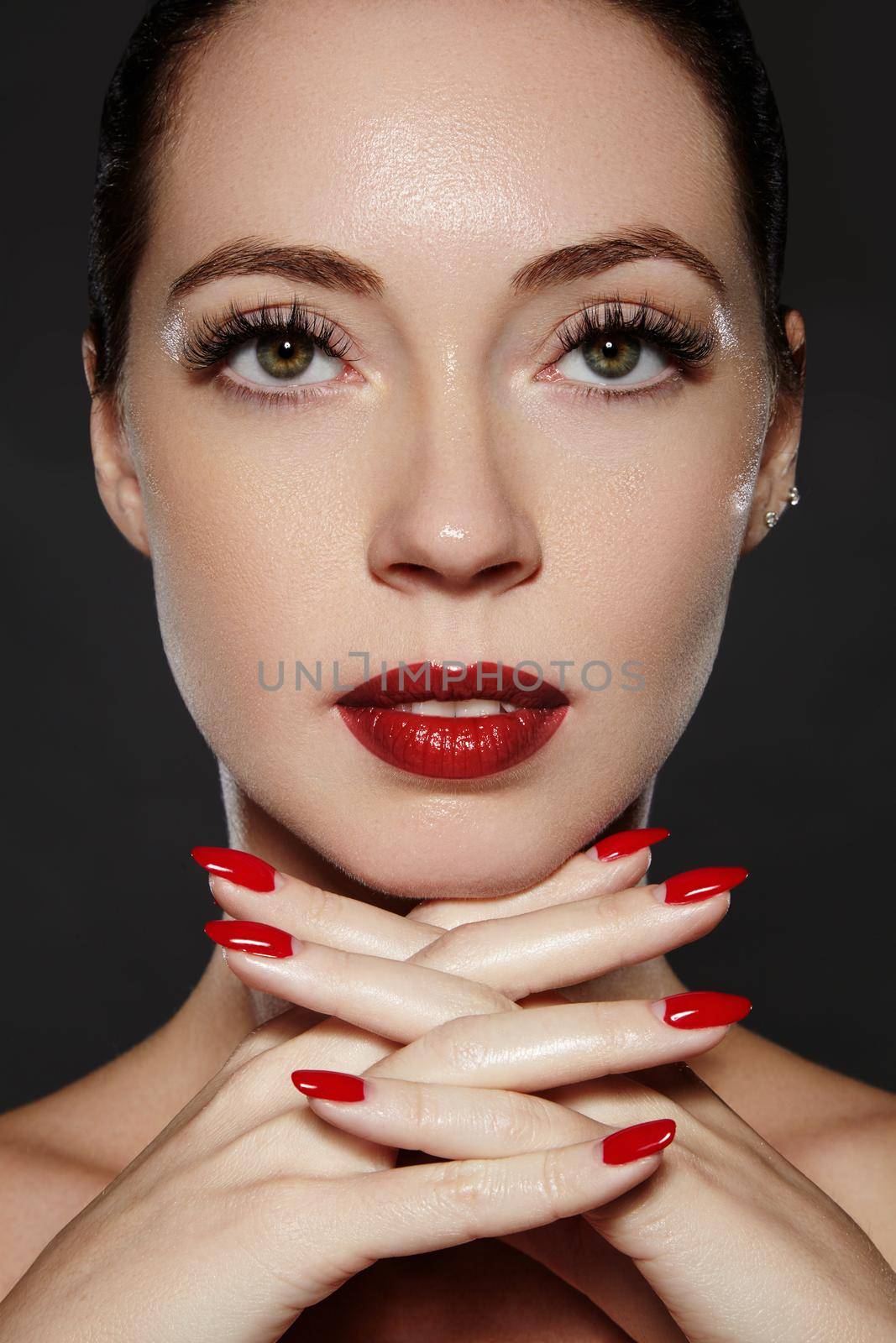 Luxury woman style vamp. Cosmetics, manicure on nails with bright red polish. Dark red lips make-up and nail color. Beauty close-up portrait of female model with red lipstick and clean skin