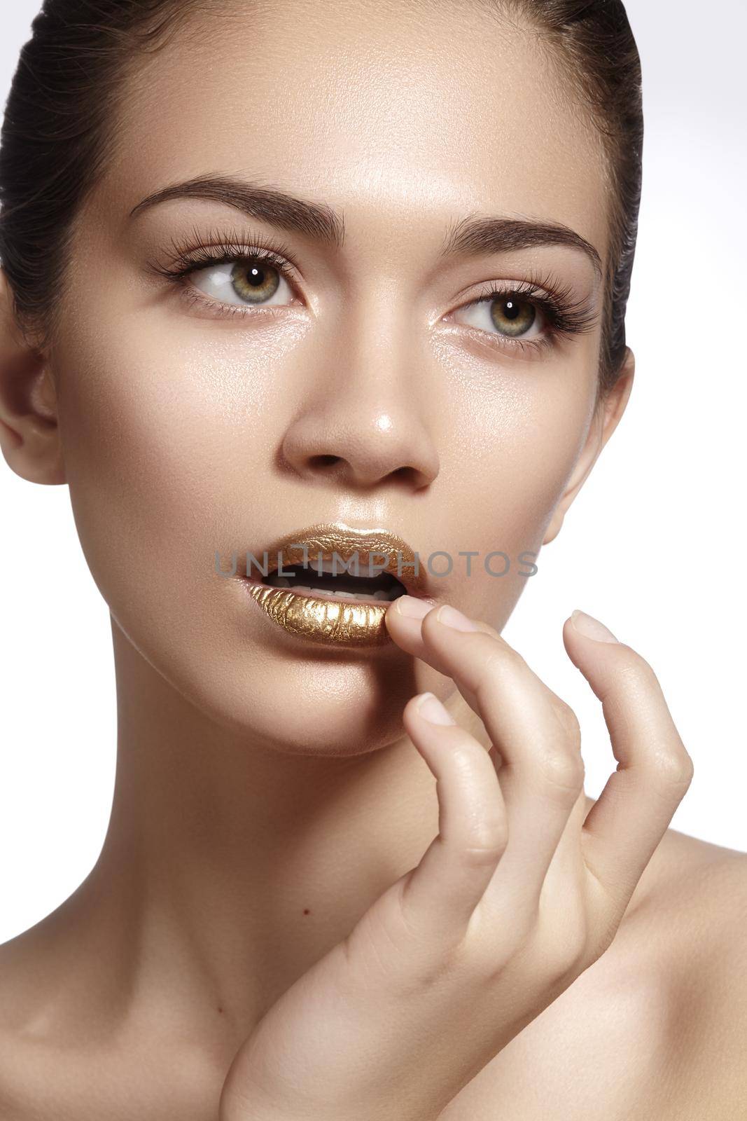 Young Beautiful Woman with clean soft Skin, bright gold Lips Makeup. Perfect eyebrows shapes. Day look make-up with gloss