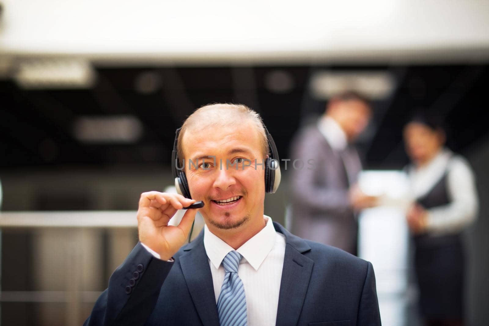 Businessman in the office on the phone with headset, looking camera
