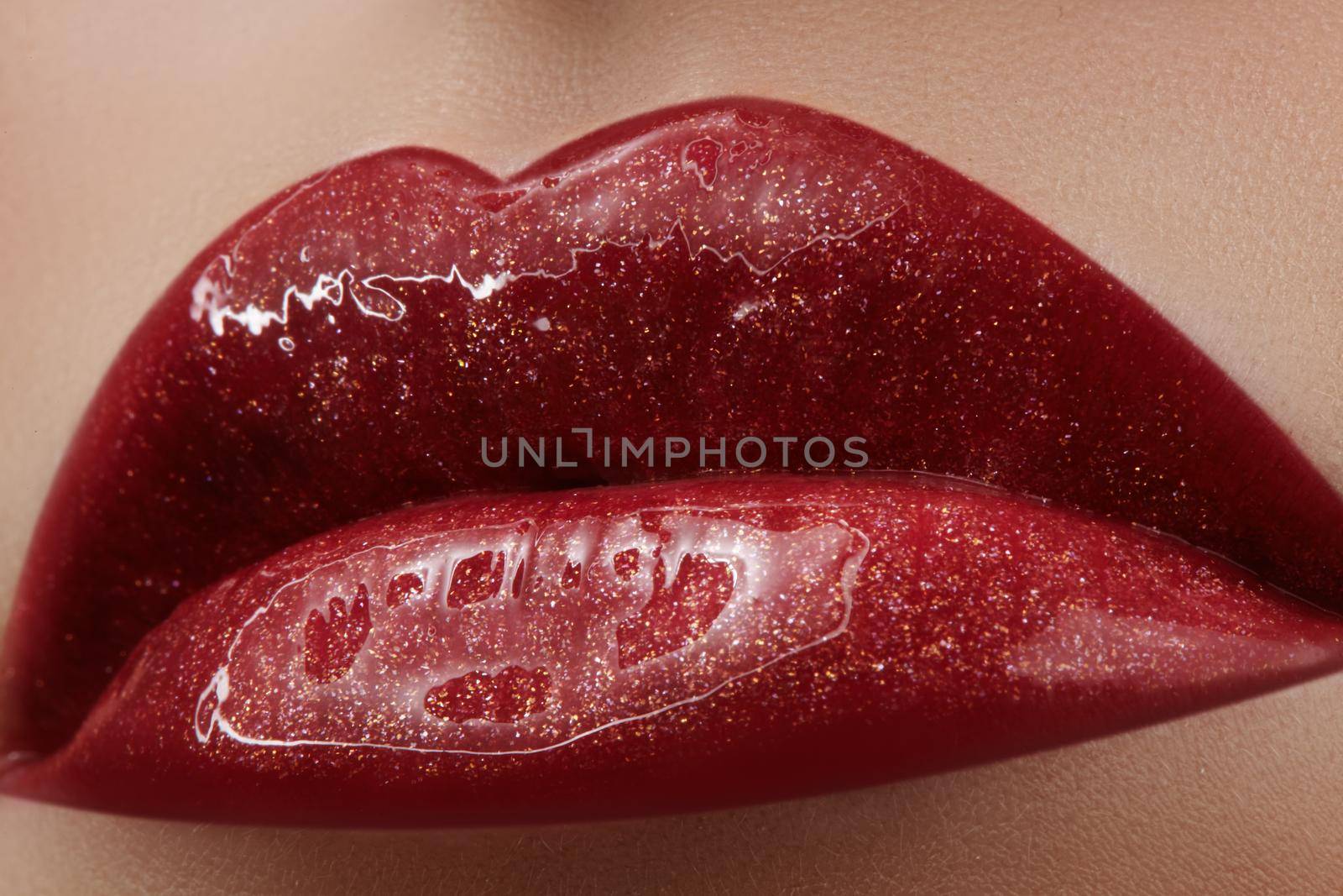 Close-up of female lips with bright makeup. Macro of woman's face. Fashion lip make-up with red gloss.Red lipgloss makeup on full female lips