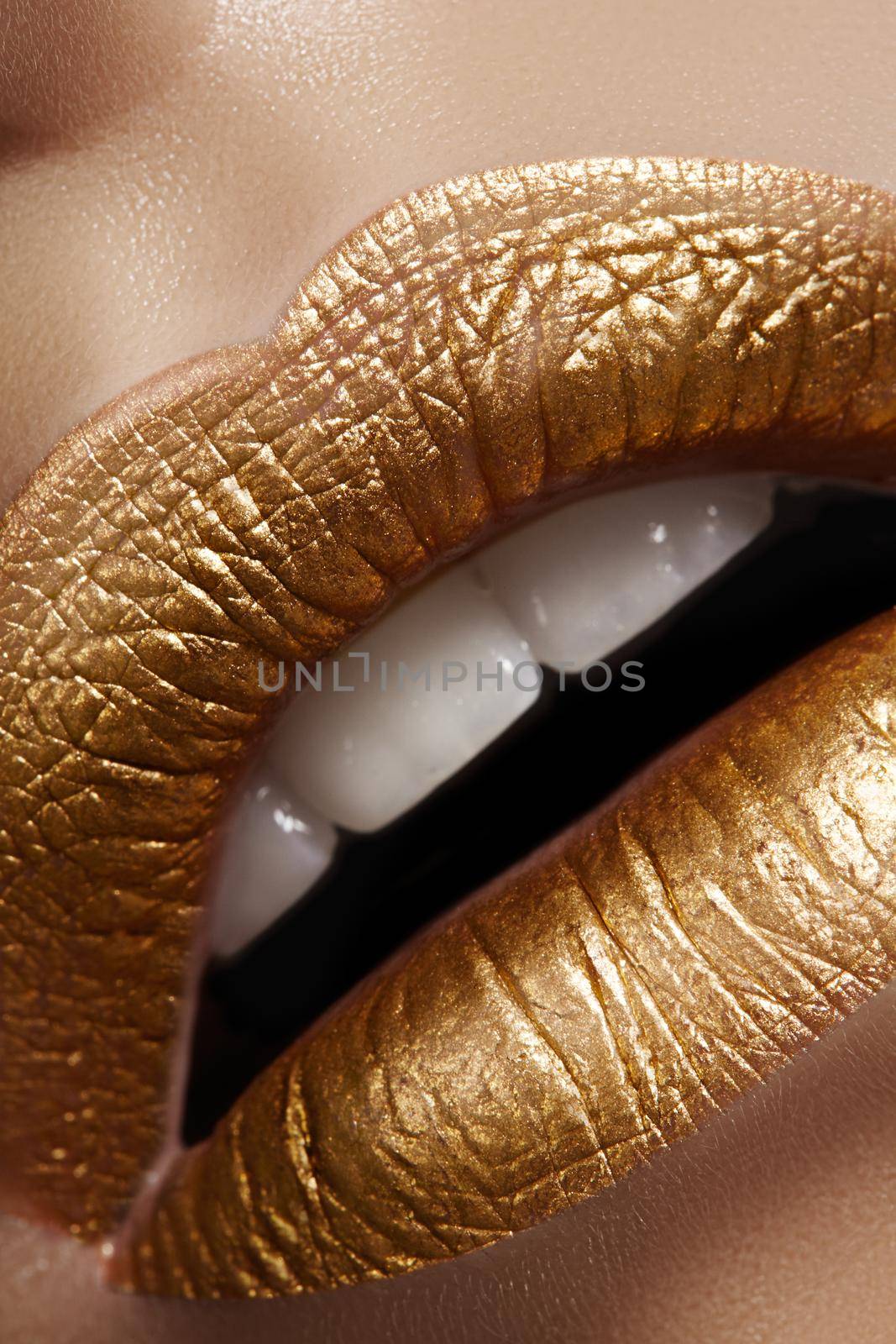 Beautiful closeup with female plump lips with gold color makeup. Fashion celebrate make-up, glitter cosmetic. Shine christmas style. Metalic makeup