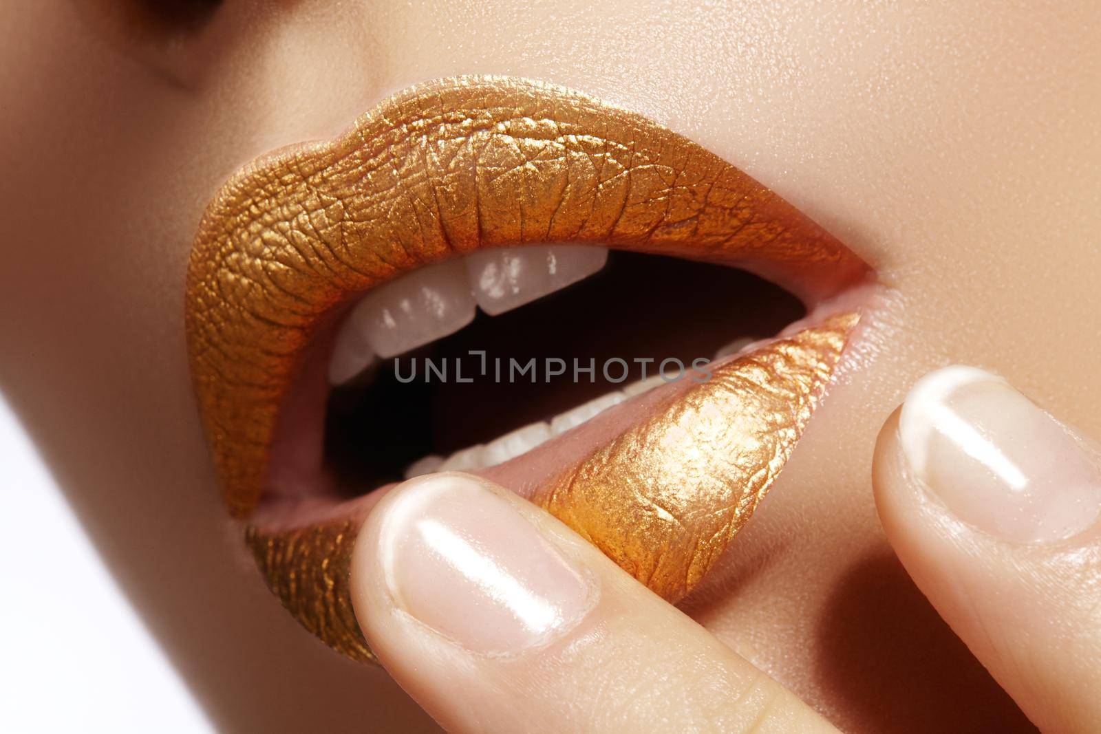Beautiful closeup with female plump lips with gold color makeup. Fashion celebrate make-up, glitter cosmetic. Shine christmas style. Metalic makeup