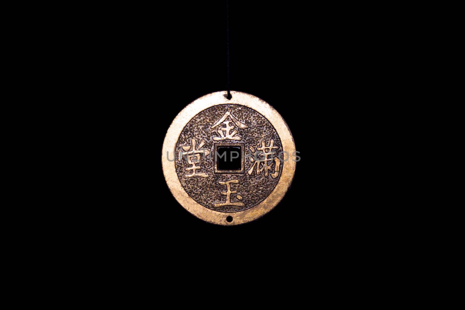 Coin talisman of feng shui on a black background close-up.