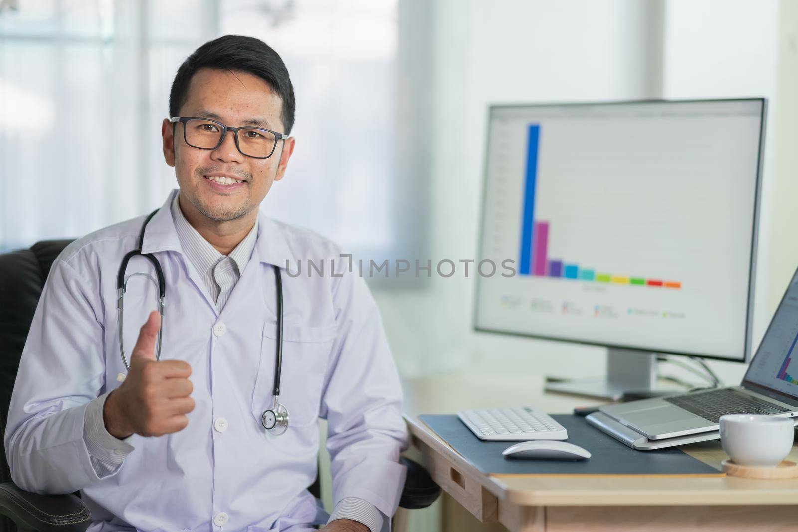 Doctor thumbs up smilling and working with laptop computer Male doctor work at office hospital. Health hospital concept