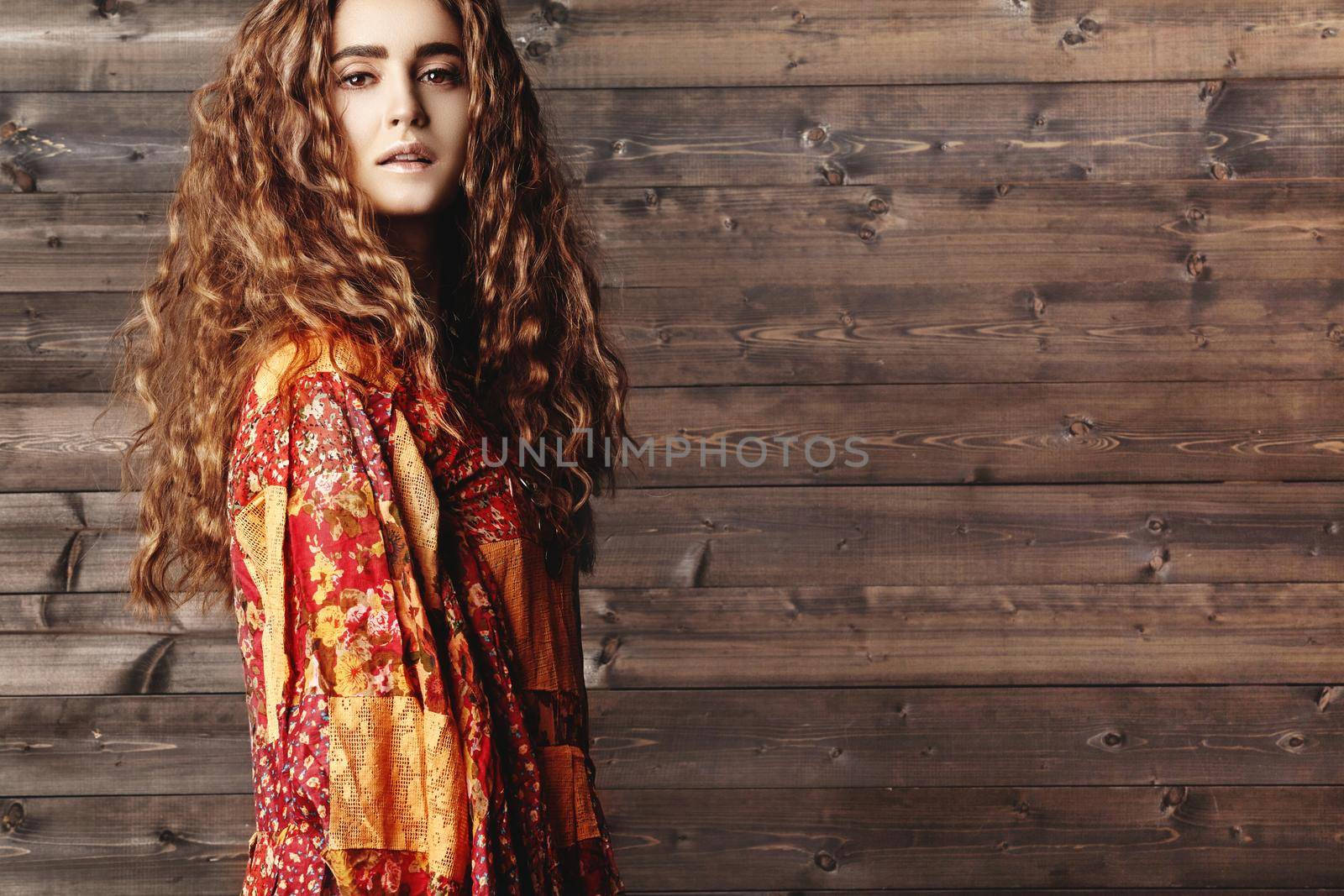 Beautiful young woman with long curly hairstyle, fashion jewelry with long brunette hair. Sexy girl in vogue style. Pretty arabian beauty portrait of female face. Indian style clothes, long dress
