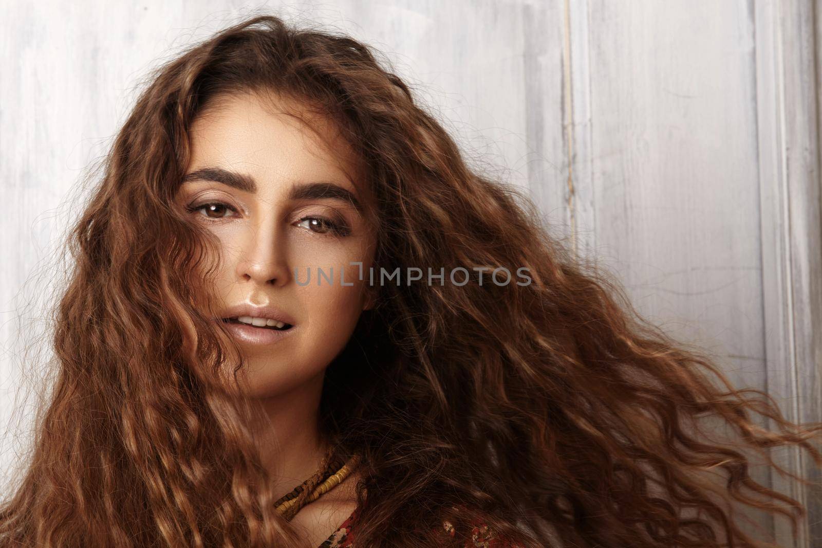 Beautiful young woman with long curly hairstyle, fashion jewelry with long brunette hair. Sexy girl in vogue style. Pretty arabian beauty portrait of female face. Indian style clothes, long dress