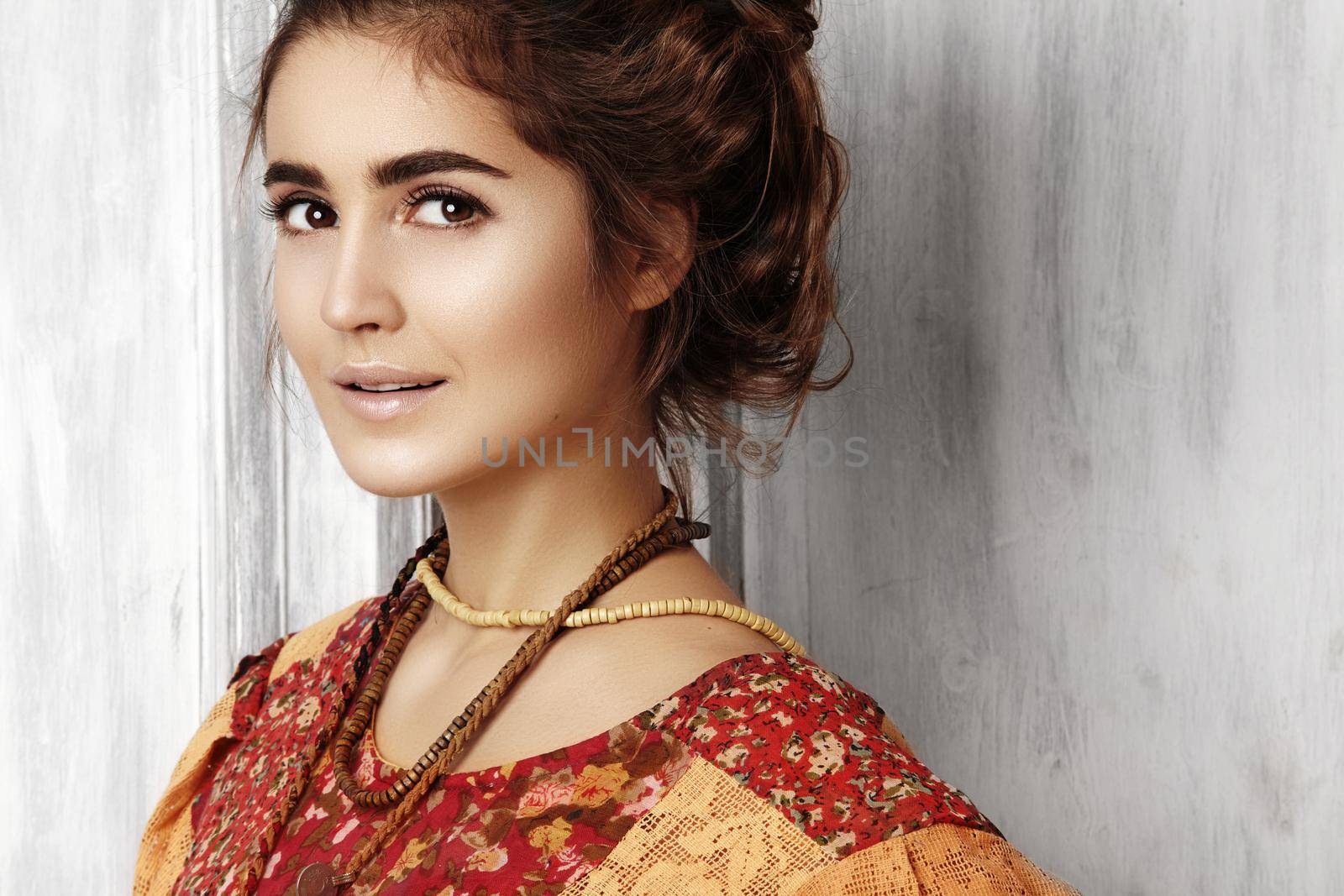 Beautiful young woman with long curly hairstyle, fashion jewelry with long brunette hair. Sexy girl in vogue style. Pretty arabian beauty portrait of female face. Indian style clothes, long dress