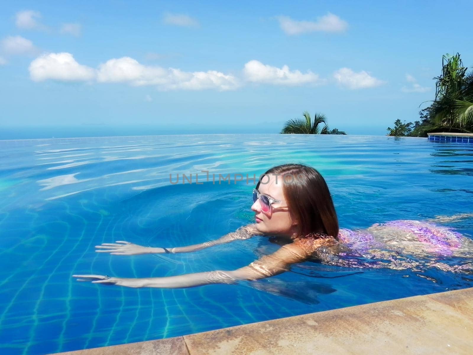beautiful young european woman in the swimming pool near the ocean, spa, relaxing, tropical, vacation.