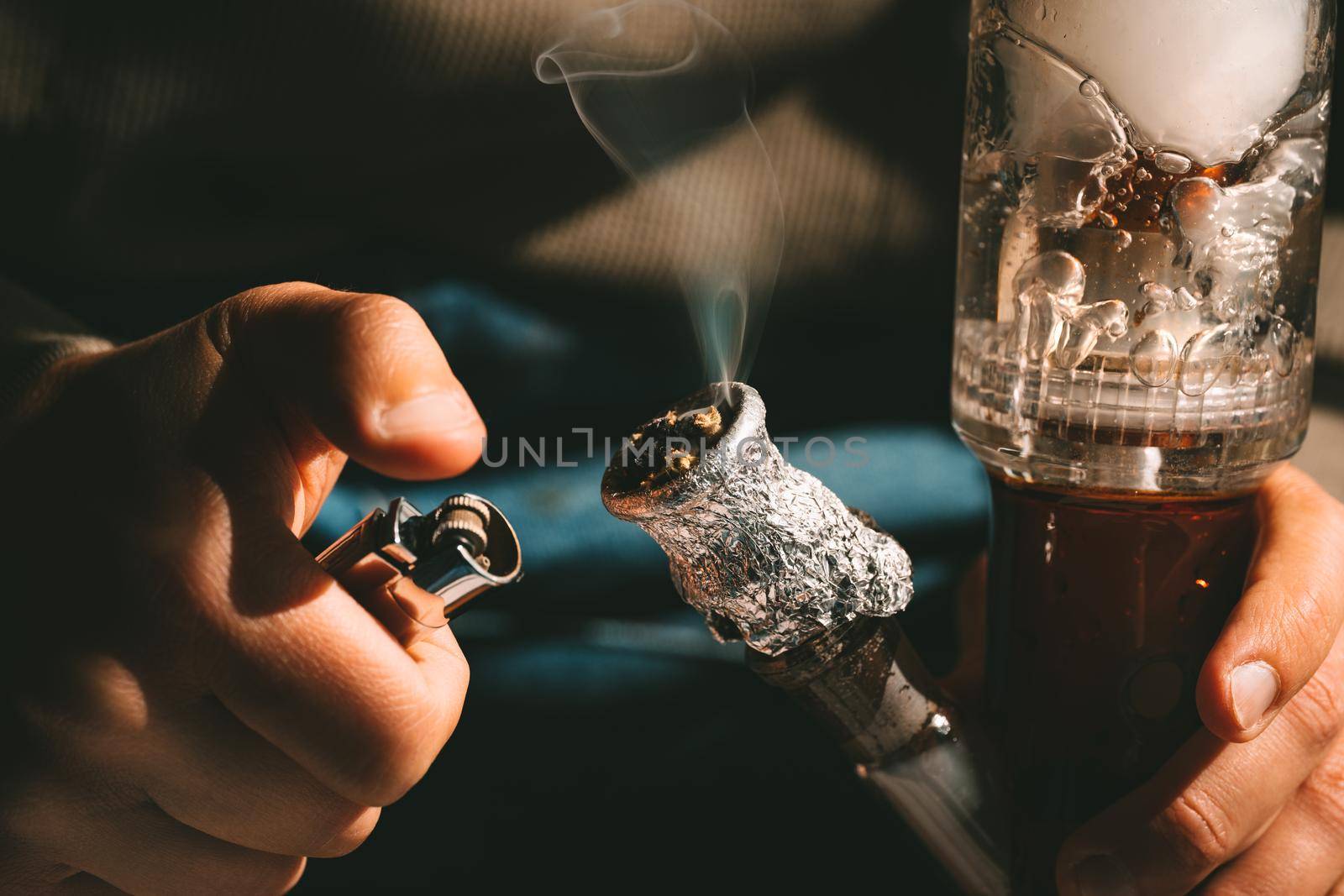 Close up of man smoking pot, medical marijuana or cannabis from a bong or water pipe. Cannabis and weed legalisation concept by DariaKulkova