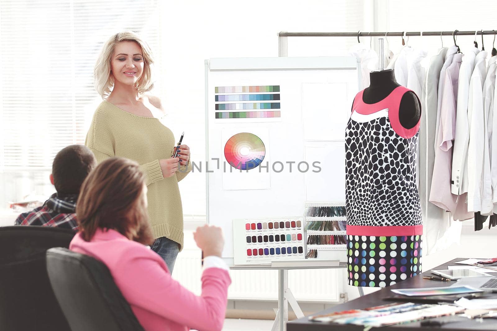 woman pointing at swatch color palette while discussing what color to choose with colleague.
